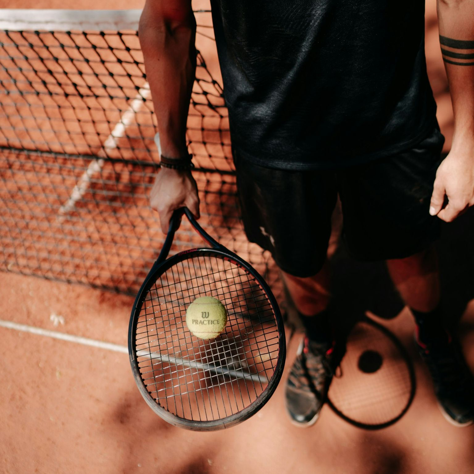 person in black shorts holding green tennis racket